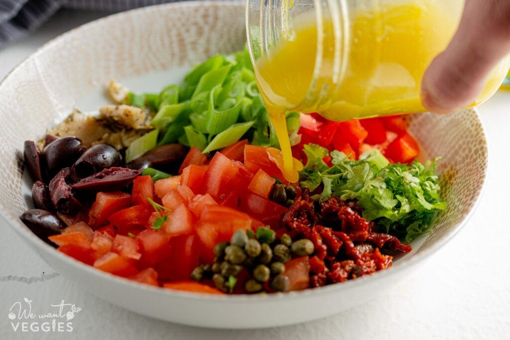 Pouring dressing onto vegetables in bowl