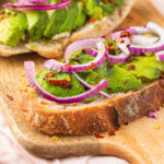 Avocado toast with red onion on a cutting board