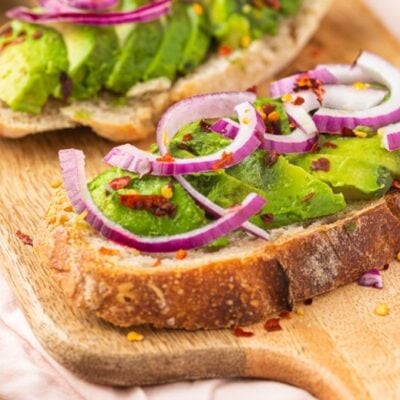 Avocado toast with red onion on a cutting board