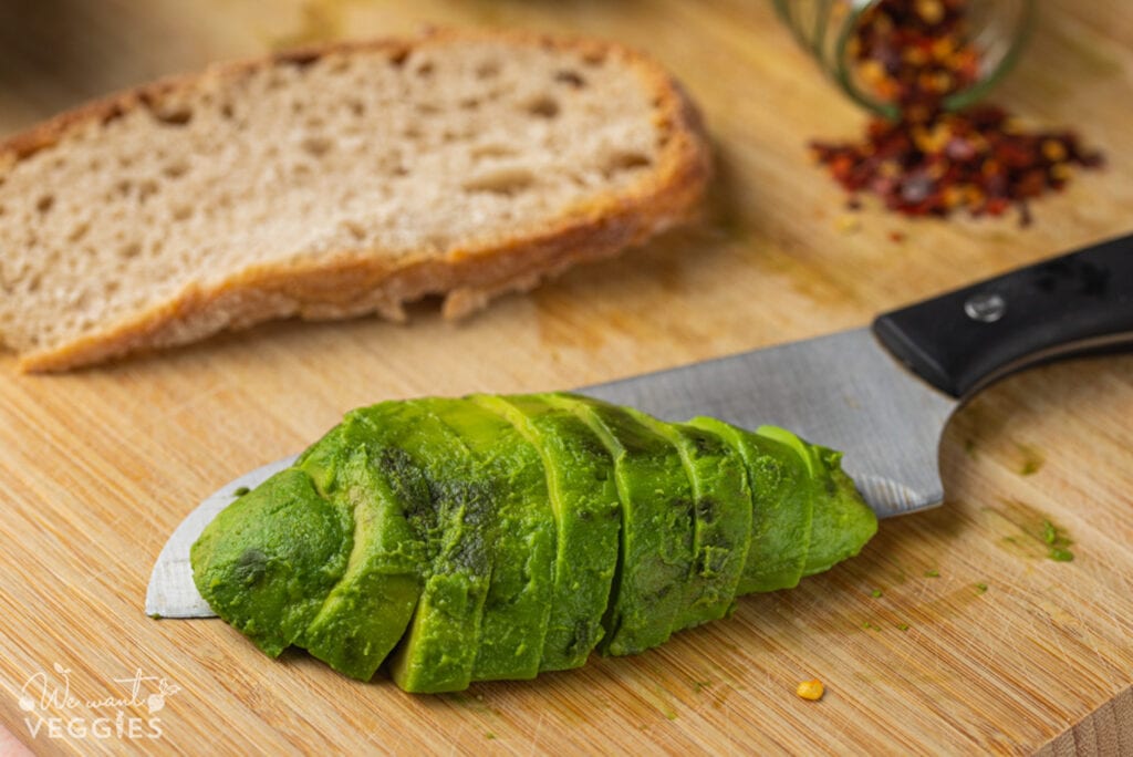 Sliced avocado on cutting board with knife