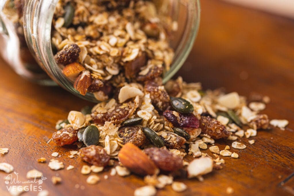 Granola spilling onto wood tabletop from jar