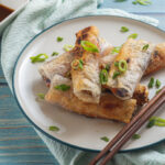 Crispy spring rolls on ceramic plate with chopsticks and soy sauce