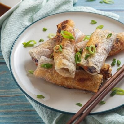 Crispy spring rolls on ceramic plate with chopsticks and soy sauce
