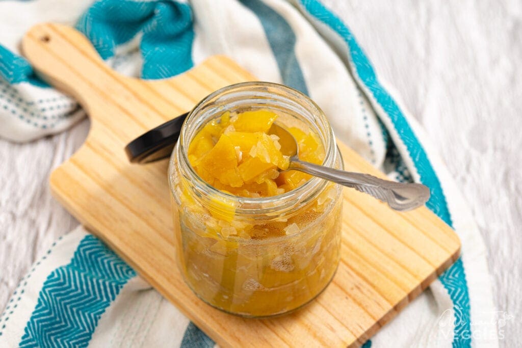 Mango chutney in jar with spoon on cutting board