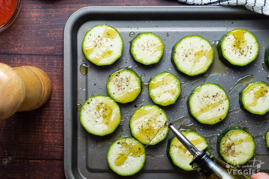 Zucchini rounds on baking pan with oil
