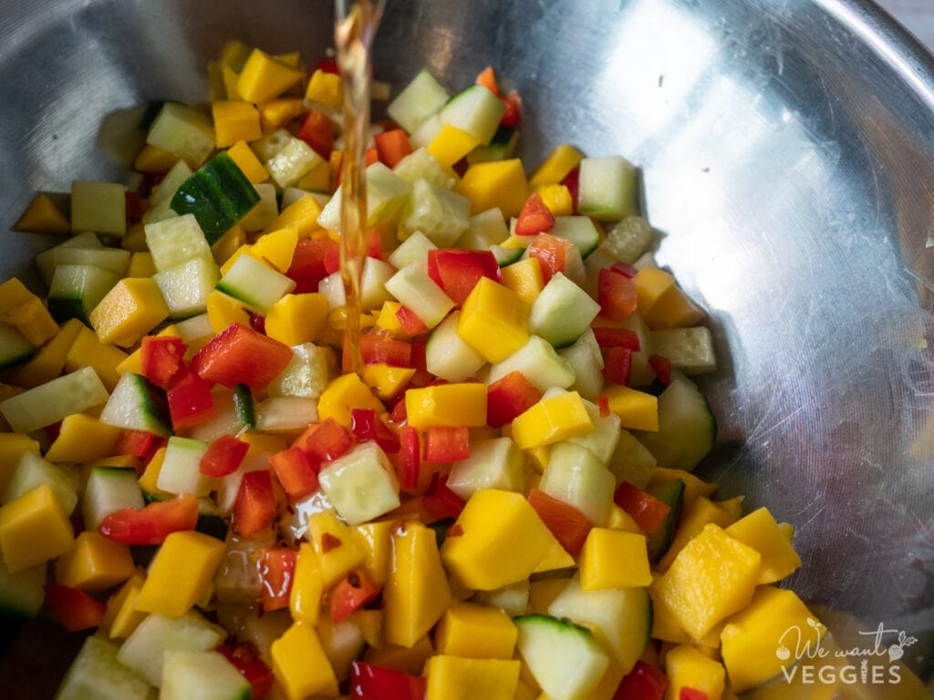 Pouring dressing onto cucumber mix.