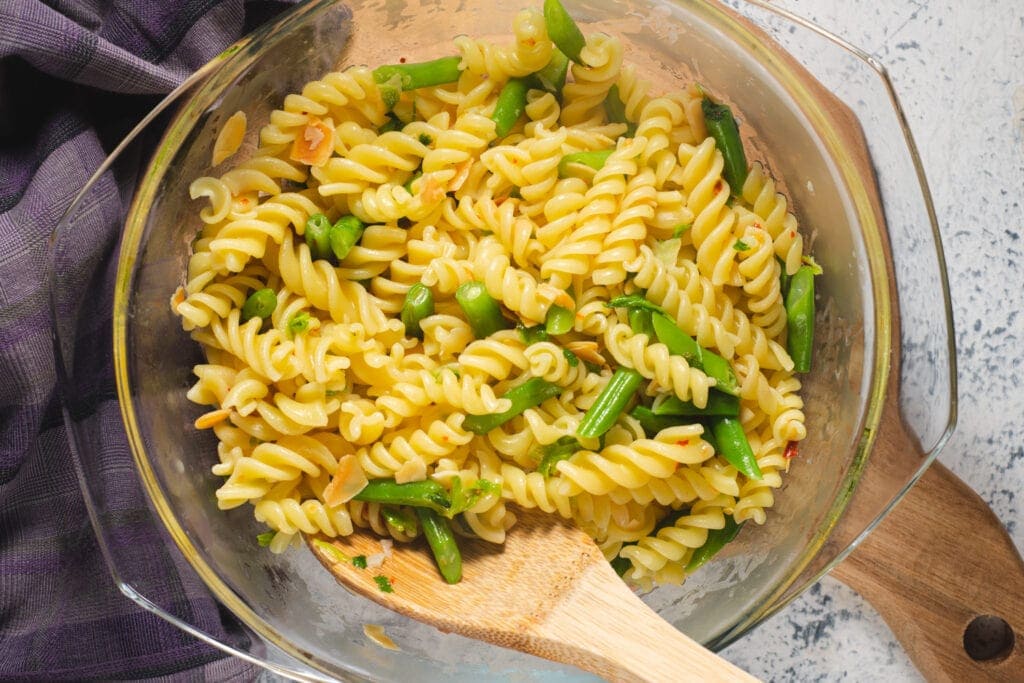 Pasta, green beans, sauce ingredients in glass mixing bowl