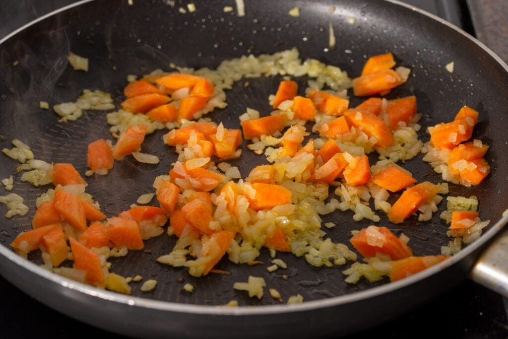 Onions and carrots cooking in a skillet