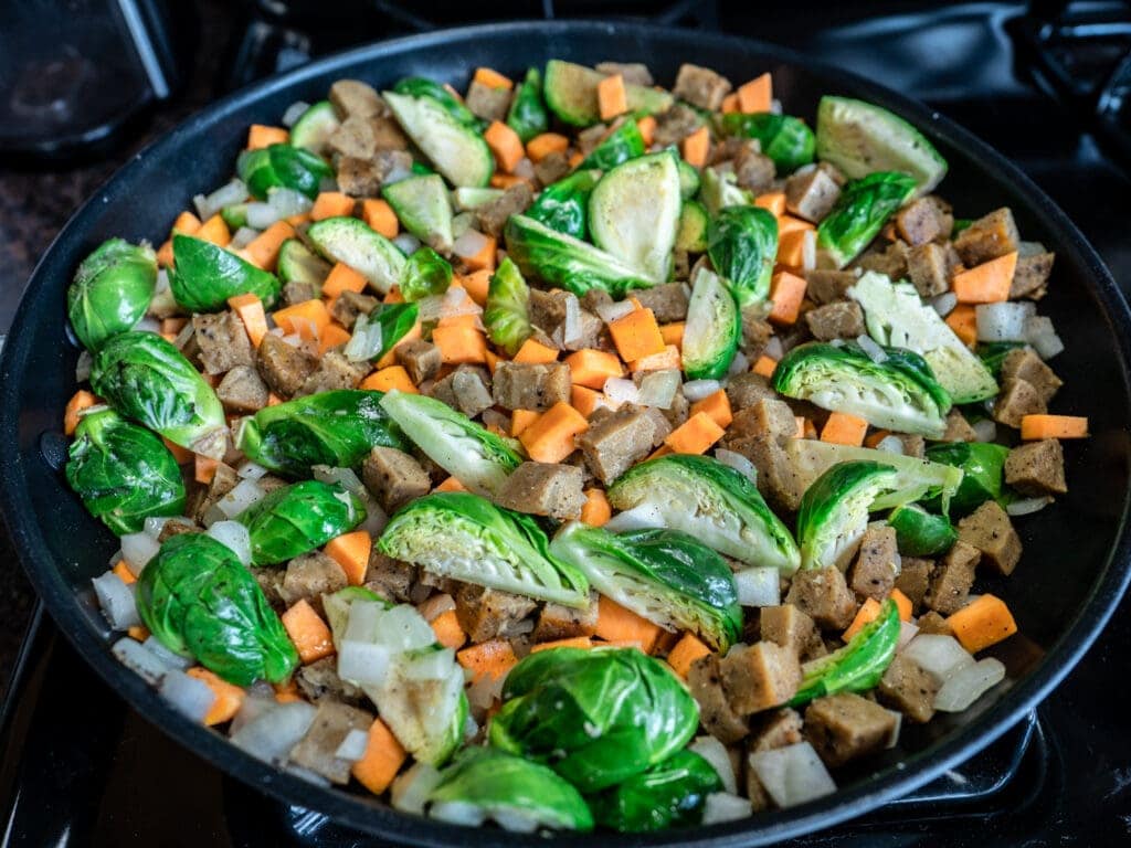 Saute plant-based sausage, Brussels sprouts, sweet potato, and onion