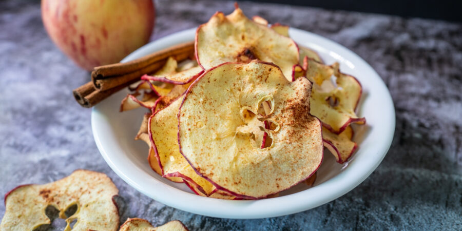 Baked apple chips in bowl with cinnamon stick