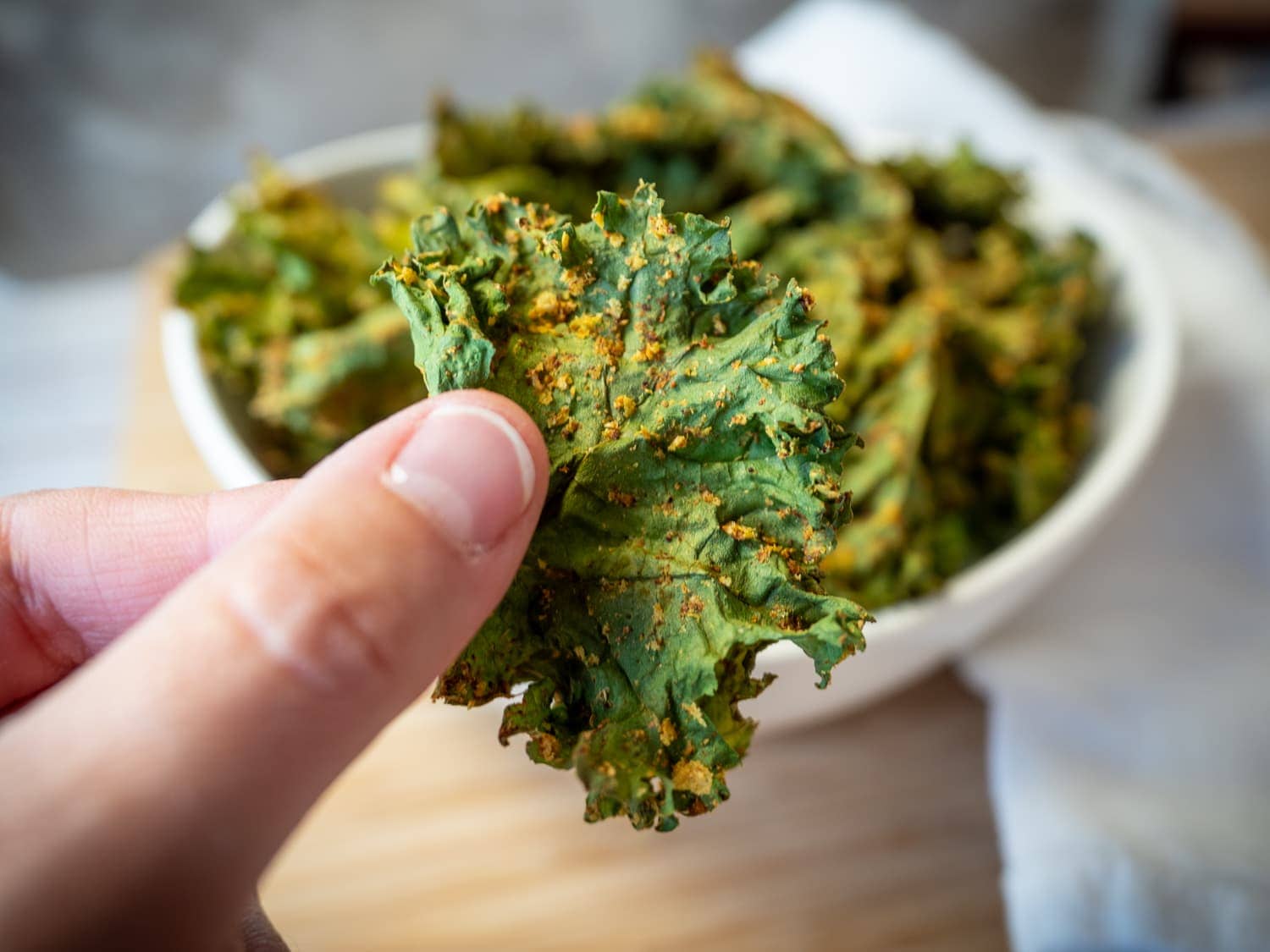 Fingers holding a kale chip